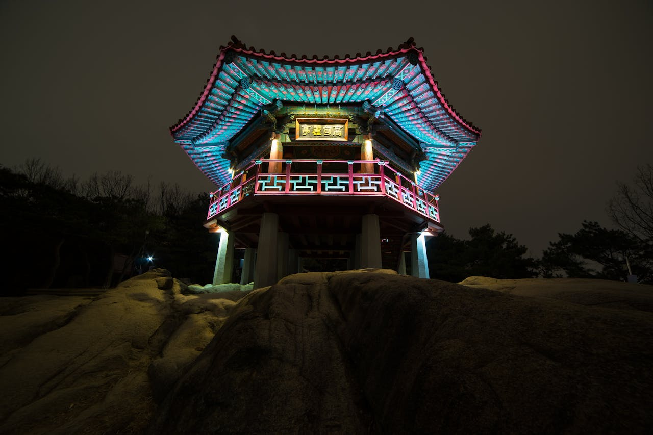 A beautifully lit traditional Korean pavilion captured at night, highlighting intricate architecture.